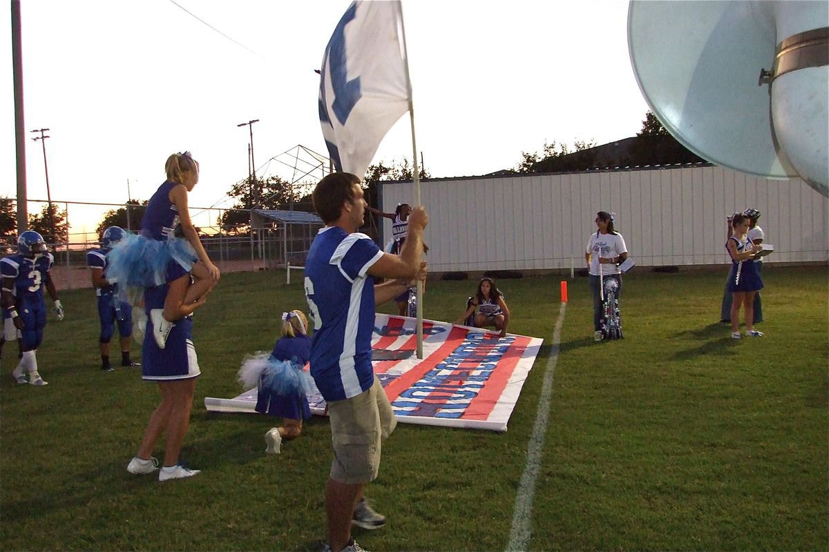 Image: Raising the flag — Milfor Bulldog player Jacob Rose(6) prepares to lead the Bulldogs onto the field.