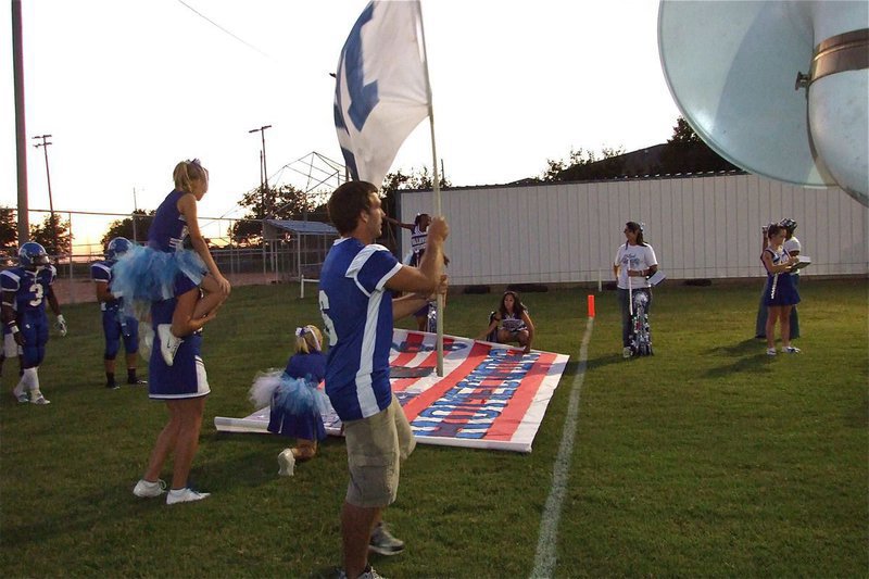 Image: Raising the flag — Milfor Bulldog player Jacob Rose(6) prepares to lead the Bulldogs onto the field.