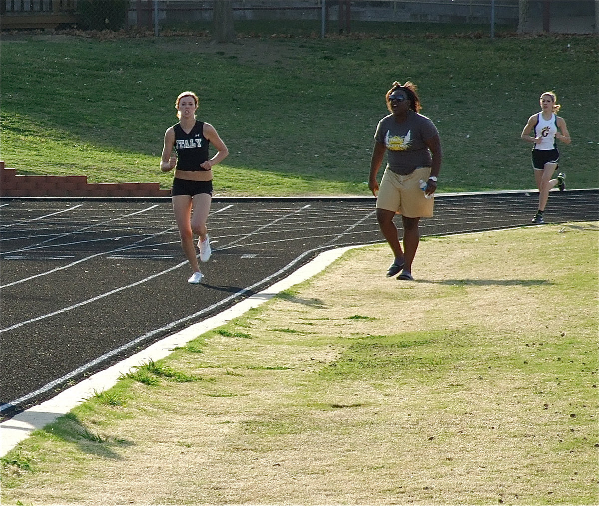 Image: Pushing each other — Jimesha Reed shouts encouragement to friend and lone Italy varsity girls’ teammate, Kaitlyn Rossa, to help Rossa finish the 1600 meter run strong.The pair combined for 24 total points and finished in 7th place out of nine schools.