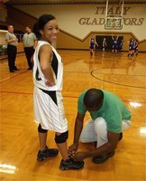 Image: Star treatment — Ryisha Copeland gets help with her shoe laces from assistant coach Erik Wilson before the start of the JV Girls game.