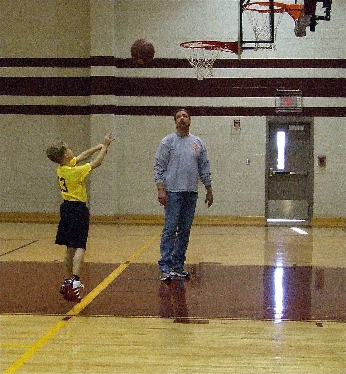 Image: Creighton goes up — Creighton Hyles(13) takes a practice jumper with dad and coach, Charles Hyles, looking on.