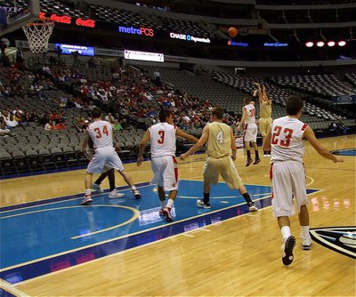 Image: Ball in flight — Italy’s Colton Campbell(5) makes use of the available airspace inside the American Airlines Center and release a shot over Mineral Wells’ Dillon Wilkins(30) as Ryan Ashcraft(4) battles Jacob Velasquez(3) for position.