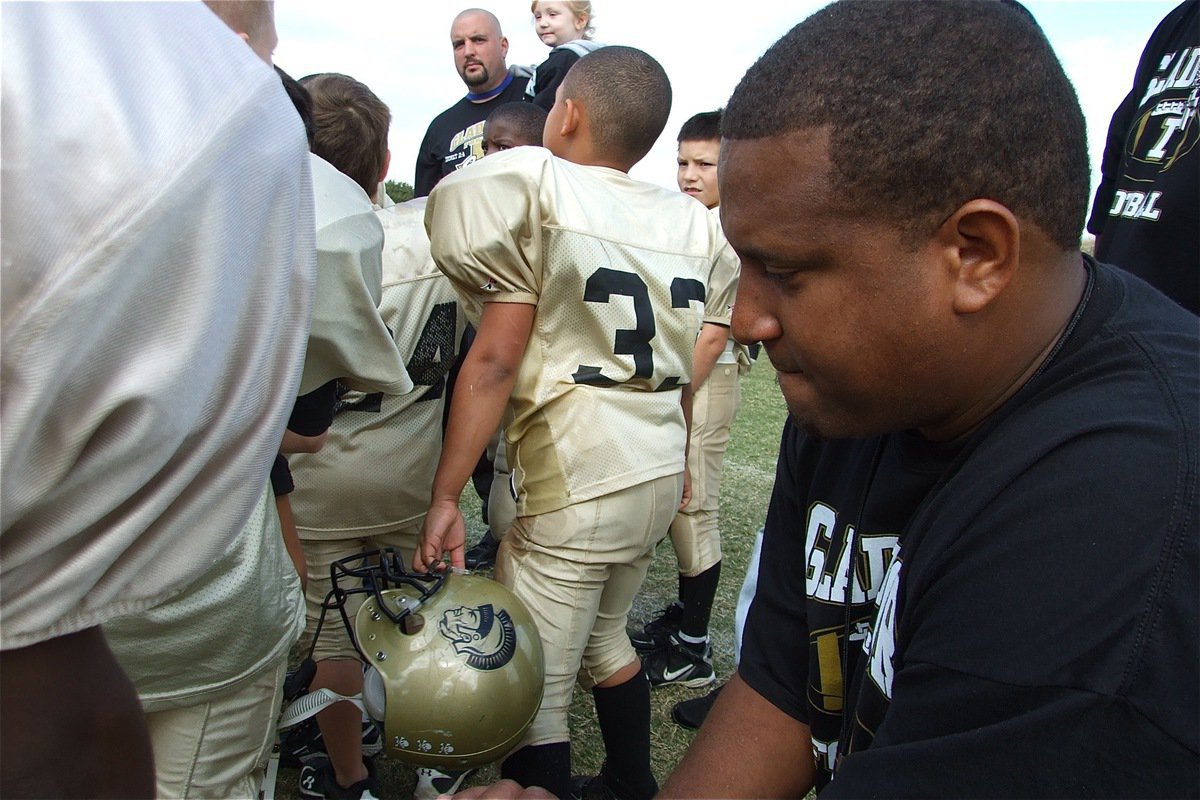 Image: Taking a moment — B-Team assistant coach Addison Alexander takes a knee, and then a moment, to reflect on the outstanding accomplishments by the B-Team Gladiators this season. The group had to win a couple of nail-biters along the way to finish undefeated at 9-0 and claim the 2010 NESA B-Division Superbowl Championship.