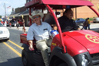 Image: The Commissioner — Ellis County Commissioner Heath Sims of Precinct 3 offers candy to the Homecoming crowd while Rupert Hernandez drives with one hand and throws candy with the other.