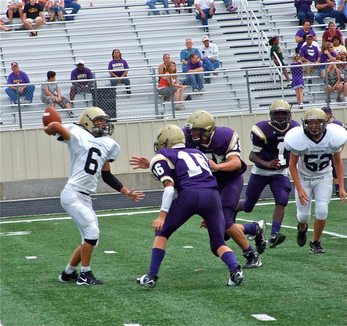 Image: Tough as nails — Italy’s JV quarterback stands in the pocket and throws a pass knowing he is about to be nailed by two Panther defenders.