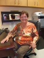 Image: Debbie Knott — Debbie Knott seated at her desk at Trinity Mission.