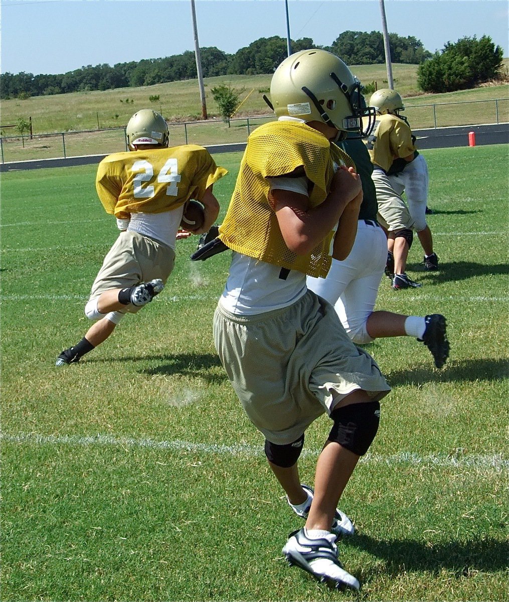 Image: Sophomore connection — J.V. Quarterback Tony Wooldridge hands off to back Chase Hamilton(24) who cuts toward daylight.