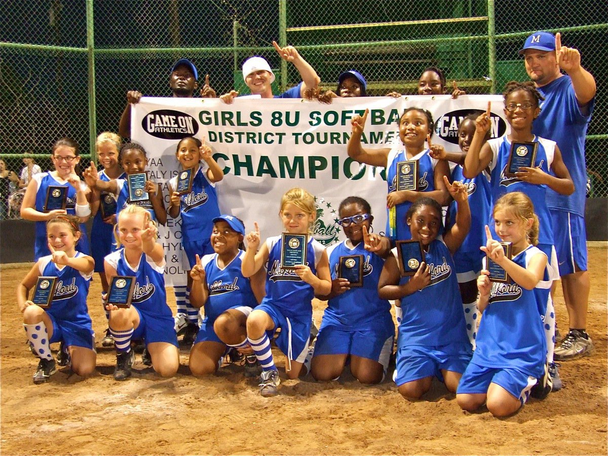 Image: Milford’s Lil’ Dogs get dramatic win to claim district championship — The Milford Lil’ Dogs celebrate their district championship victory and display their plaques and championship banner provided by Game On Athletics. Milford, along with the Ferris Scorpions, qualify for the state tournament in Clifton.