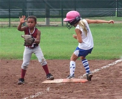 Image: Alex hits single — Alex Jones reaches first base while the Ferris Scorpions’ 6 year old first baseman Brianna Evans instructs her teammates to hold the ball.
