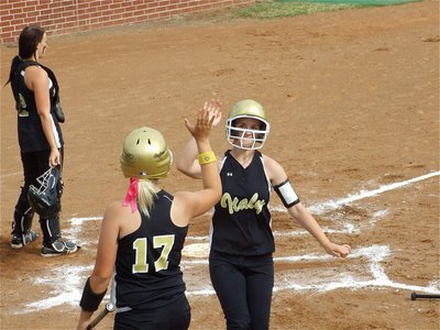 Image: The winning run — Courtney Westbrook high-fives teammate Megan Richards after crossing the plate for the first score of the game. Westbrook was brought in courtesy of a homerun hit by Anna Viers.