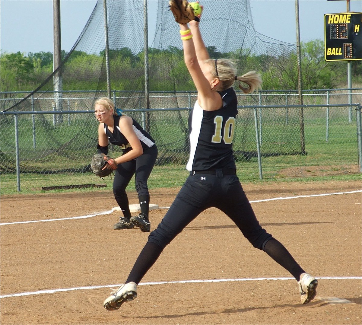 Image: Teamwork — Lady Gladiator pitcher Courtney Westbrook(10) is in the midst of her windup while third baseman Megan Richards moves in.