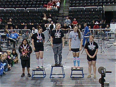 Image: On the podium — Second from the left, Kaytlyn Bales is all smiles after receiving her 3rd place state medal in 1A women’s powerlifting.
