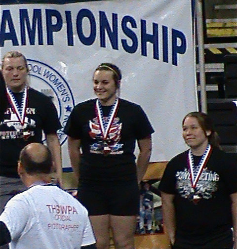 Image: Say, “Cheese!” — In the middle, an excited Kaytlyn Bales poses for the cameras with her 3rd place state medal around her neck.