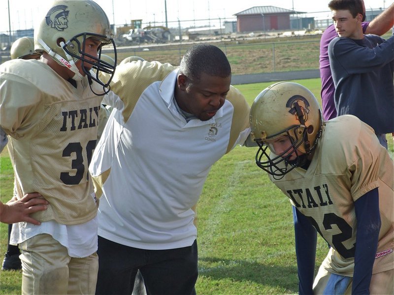 Image: Let’s try this play… — Coach Glen McClendon strategizes with Joseph Celis(30) and Austin Maynard(82) during their win over Palmer in the wildcard game.