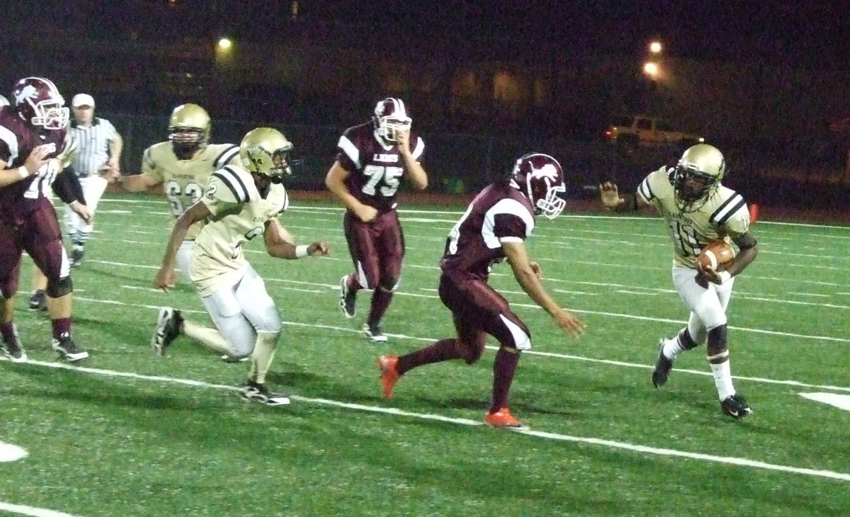 Image: Anderson waves bye — #63 Zach Hernandez and #2 Heath Clemons try to spring #11 Jasenio Anderson into the open field.