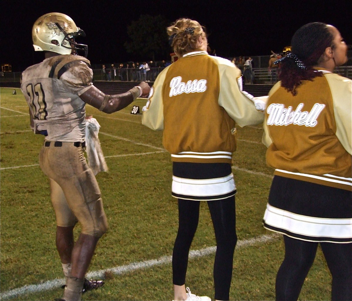 Image: Pinky pride — Covered in mud but filled with pride,  Jasenio Anderson takes time to hold Kaitlyn’s pinky during the school song.