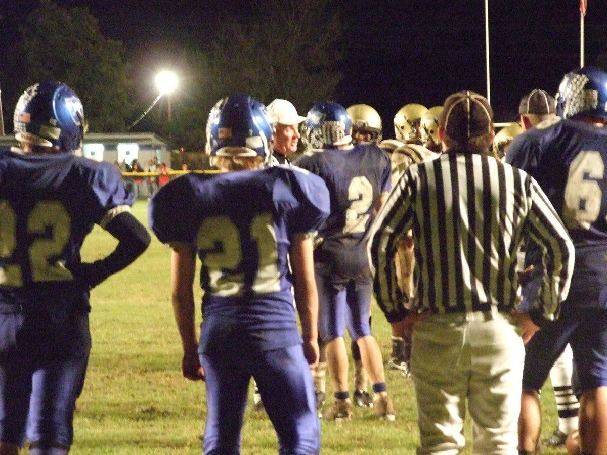 Image: Captains shake hands — The referee pulls both captains from their huddles in an effort to keep the peace.