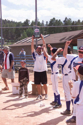 Image: We did it! — Coach Jason Moore raises the Super Series World Series Championship trophy in victory along with the players and fellow coaches of the Ellis County Renegades Baseball Team.