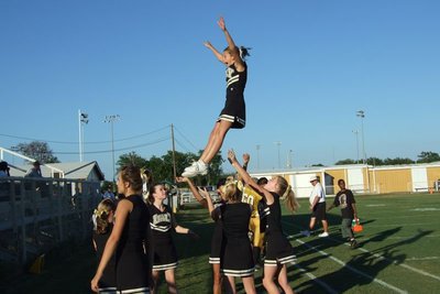 Image: Hands in the air — Not only hands are in the air as the JV cheerleaders leap up to the occasion.