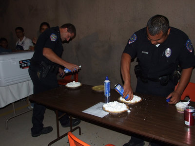 Image: Getting those pies ready — Chief Phoenix and officer Mannie Valdez getting the yummy pies ready for the pie eating contest.