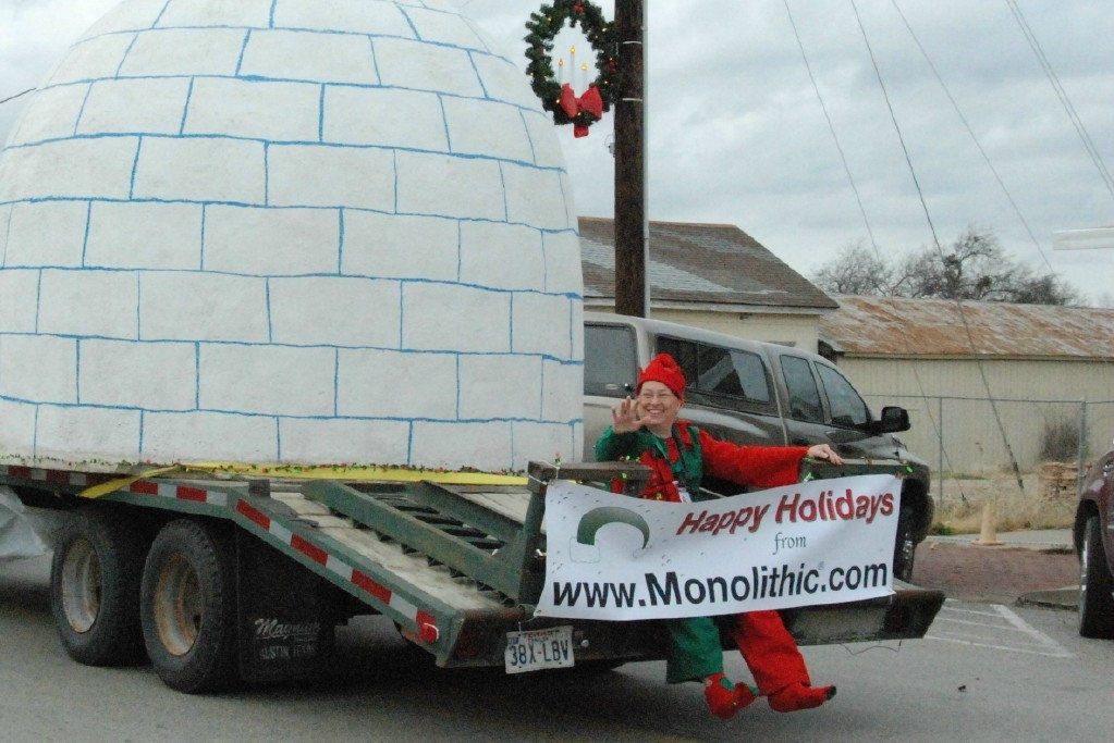 Image: Happy Trails — A very happy elf, Anne Sutherland, rides and waves at parade goers from the back of the Italy Neotribune / Monolithic float.