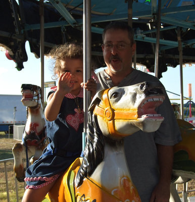 Image: Doug Betancourt enjoys a whirl on the merry-go-round with his daughter, Katy.