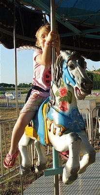 Image: Azlin Itson hangs on while riding the merry-go-round.