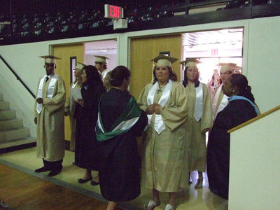 Image: The graduates line up for the entrance.  Mrs. Richards, Mrs. Davis and Mrs. Moreland are happy help the seniors.