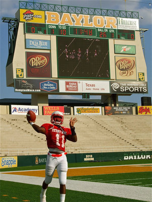 Image: Jasenio Anderson(11) kicks off to start the 2011 FCA Victory Bowl and then hustles back to the sideline to throw practice passes with the Baylor scoreboard in the background.