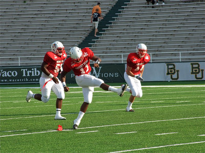 Image: Italy’s, Jasenio Anderson(11), does the honor of kicking off to start the 2011 FCA Victory Bowl as Copperas Cove’s Daquon Bratcher(52) and Crawford’s Kole Johnston(44) charge downfield.