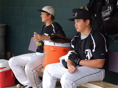 Image: Bailey Walton relaxes with a bottle of Gatorade while teammate Zain Byers ices down his throwing arm before the first game of a doubleheader.
