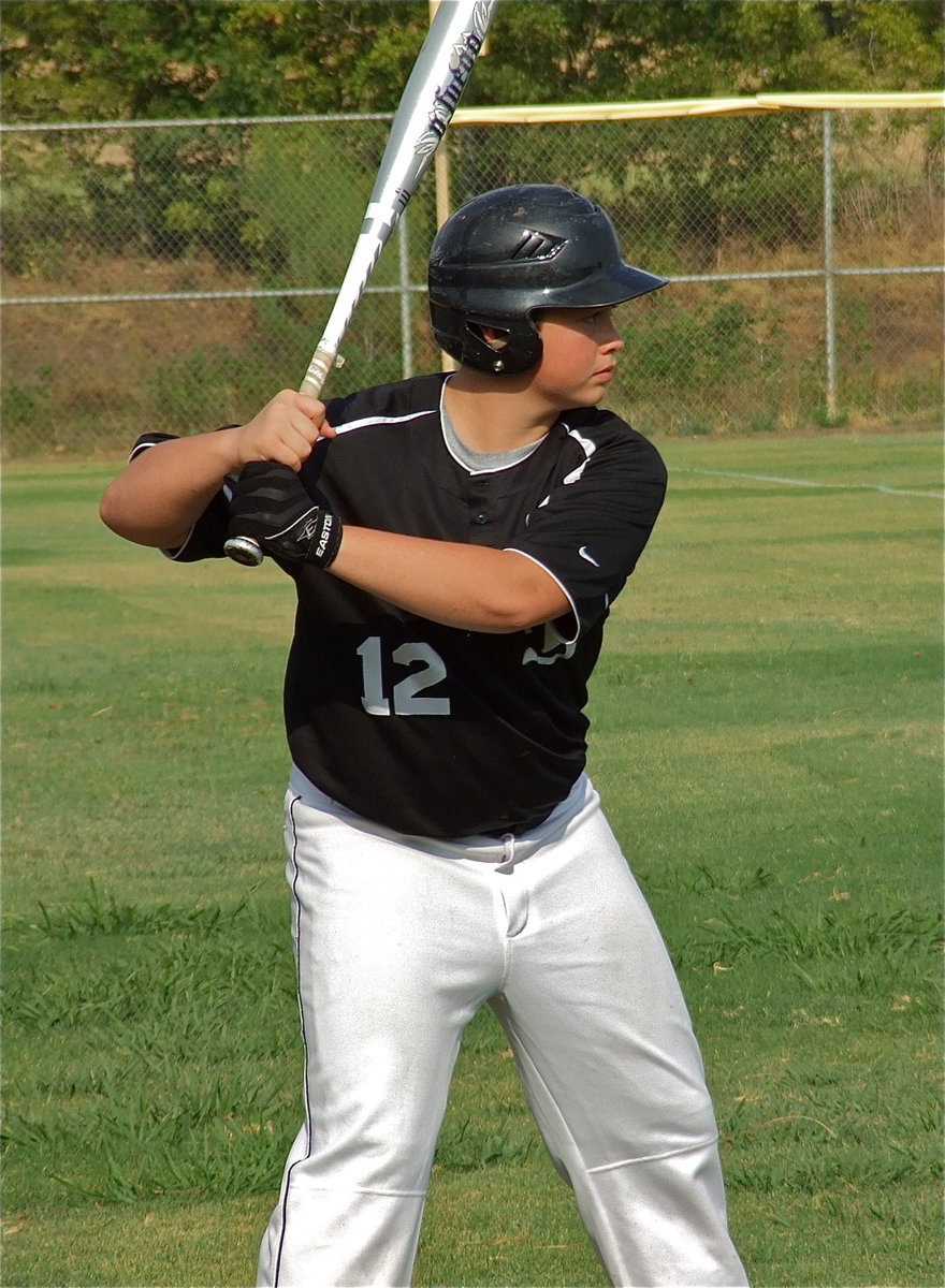 Image: Zain Byers tries to time his swing with the pitcher while warming up on the side.