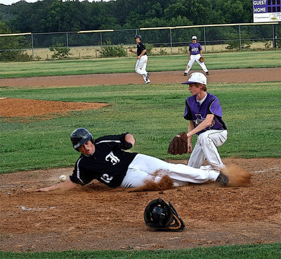 Image: Zain Byers(12) slides in to steal home while teammate Bailey Walton takes second base.