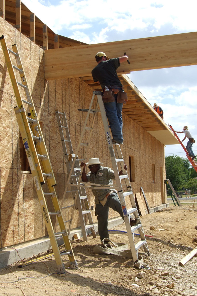 Image: Ervin Green, Sr., holds the ladders for one of the Baptist Church Builders of Texas volunteers.