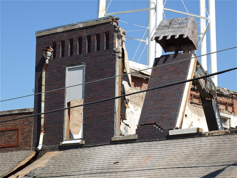 Image: An excavator rips down walls from the second story.