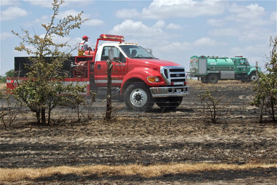 Image: Local fire departments worked in conjunction with the Texas Forest Service, temporarily stationed in Hillsboro during this current heat wave, to contain the grass fire before the winds could fuel its momentum.