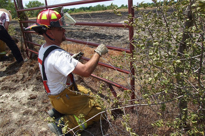 Image: Italy firefighter, Brad Chambers, helps repair one of the gates the fire departments used to gain access into a nearby pasture.