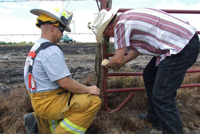 Image: Italy firefighter, Michael Chambers, helps the land owner tie the gate back into place.