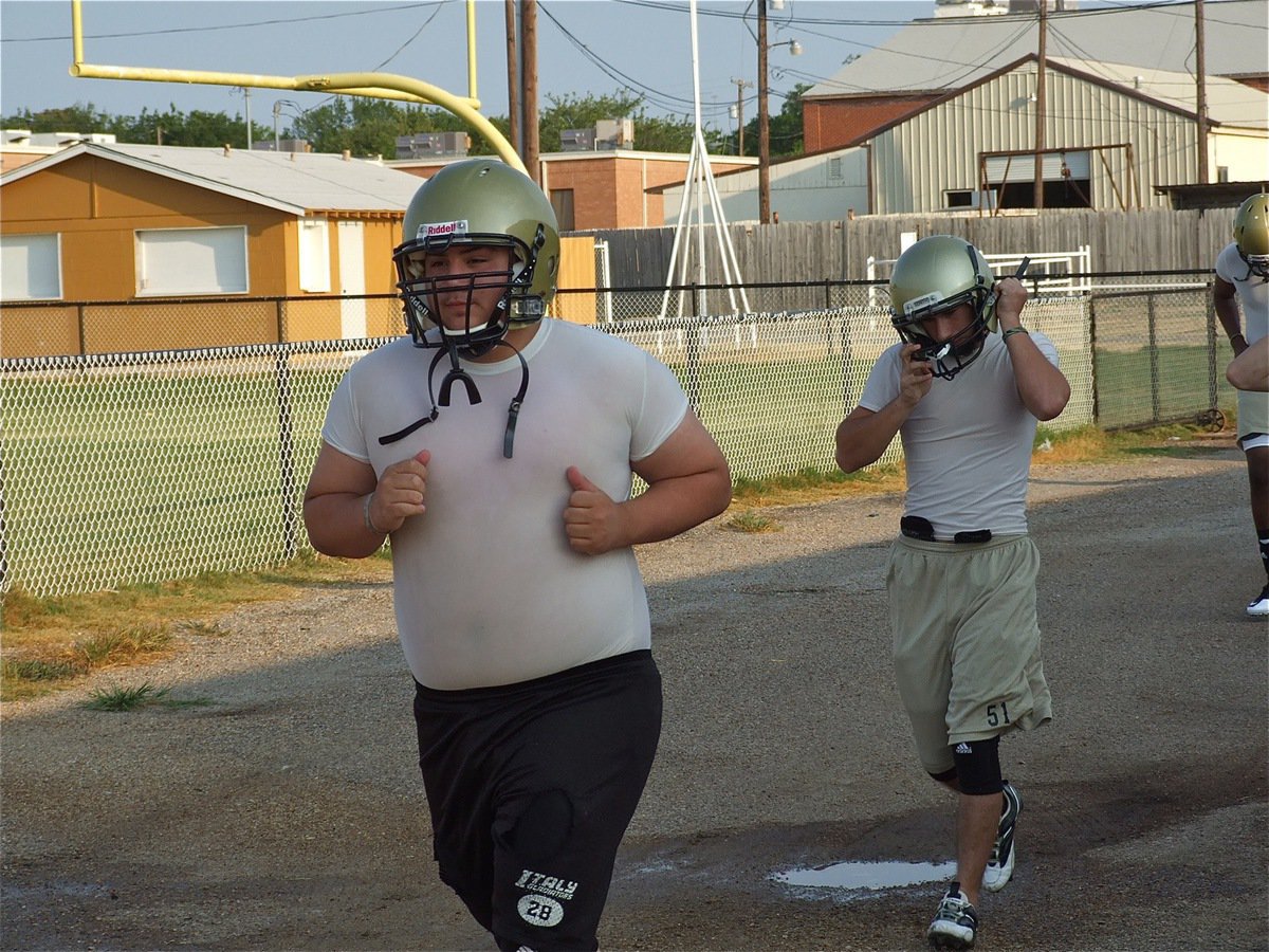 Image: Isaac Medrano and Tony Wooldridge exit the field house and head down to the practice field at the start of 2-a-day workouts on Monday.