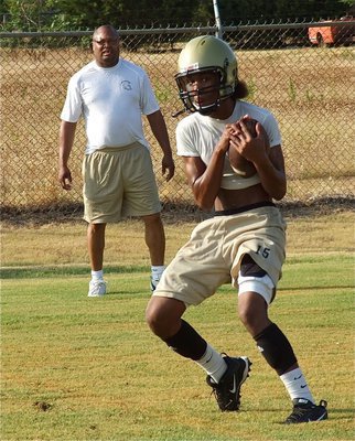 Image: Coach Larry Mayberry, Sr. looks on as Trevon Robertson hauls in a pass.