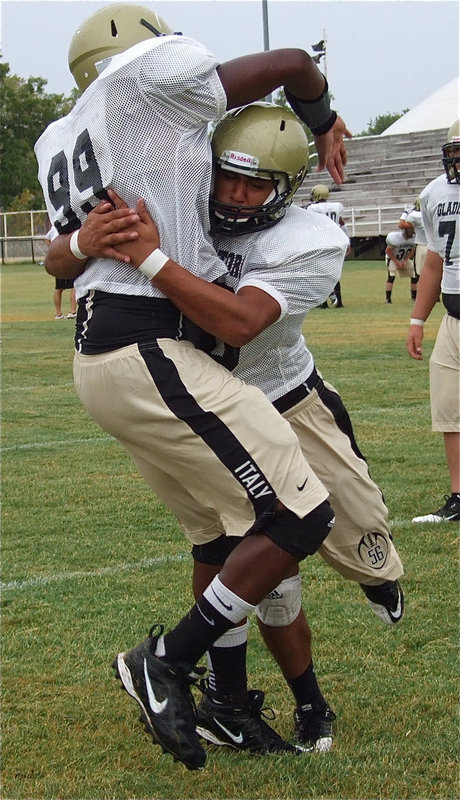Image: Gladiator, Omar Estrada pops teammate Larry Mayberry, Jr.(99) during tackling drills before the start of the scrimmage between Italy and Valley Mills.