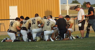 Image: The varsity take a little time on their knee before the scrimmage.
