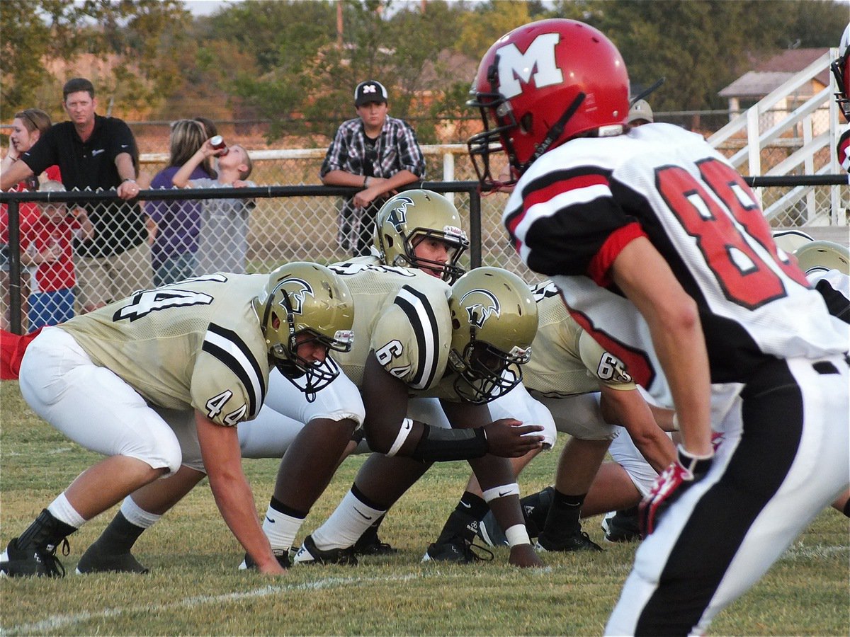 Image: Jase Holden(3) peers over his offensive line as Ethan Saxon(44) and Adrian Reed(64) prepare to block.