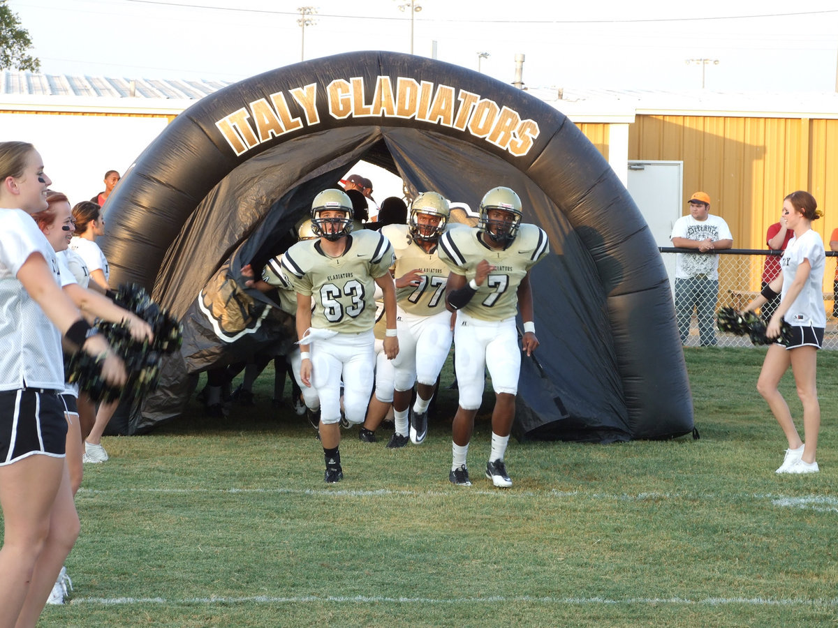 Image: Brandon Souder(63), Paul Harris(7) and Larry Mayberry, Jr.(77) lead the Gladiators onto Willis field to take on Maypearl.