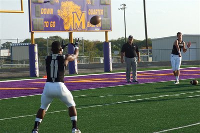 Image: Gladiator head coach Craig Bales looks on as quarterback Jase Holden delivers a warmup pass to Jalarnce Jamal Lewis.