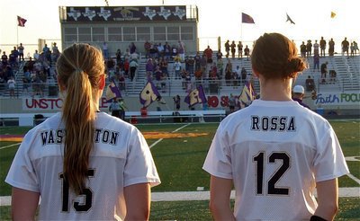 Image: Madison Washington and Kaitlyn Rossa respectfully watch Mart’s sideline sing their school song.