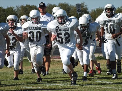 Image: Here comes Coach Richters and the Italy Jr. High Gladiators! Helping to lead the way are Devon Bowles(33), Hunter Ballard(30), Michael Hughes(52), Kevin Johnson(18) and Cameron Carter(10).