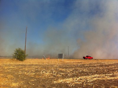 Image: A prolonged drought has left nearby fields dry as the fire threatens to consume the area.