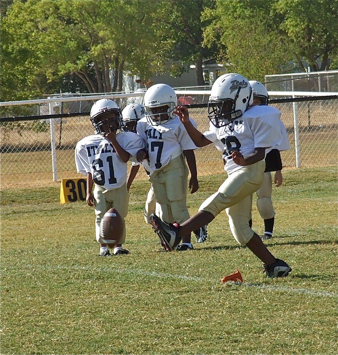 Image: Julius Williams(88) kicks off as teammates Curtis Benson(61) and Joseph Phillips(97) contemplate running down the field and making a tackle.