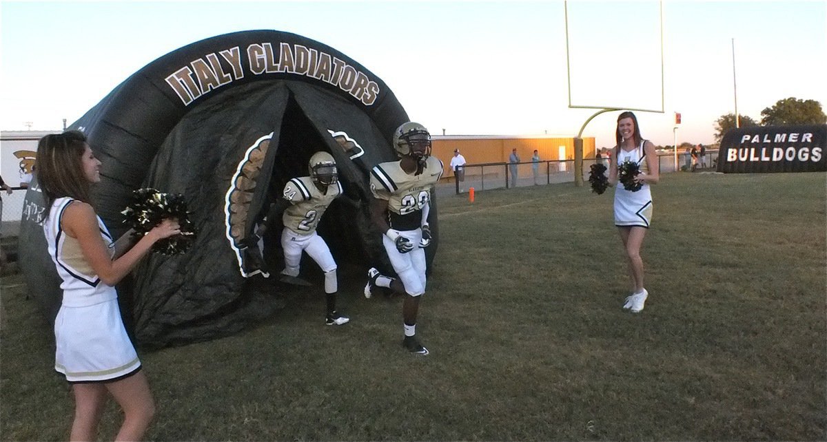 Image: Italy High School cheerleaders Beverly Barnhart and Kaitlyn Rossa cheer as Trevon Robertson(20) and Eric Carson(24) blast their way out of the tunnel as the Italy Gladiators prepare to challenge Palmer in a non-league matchup.